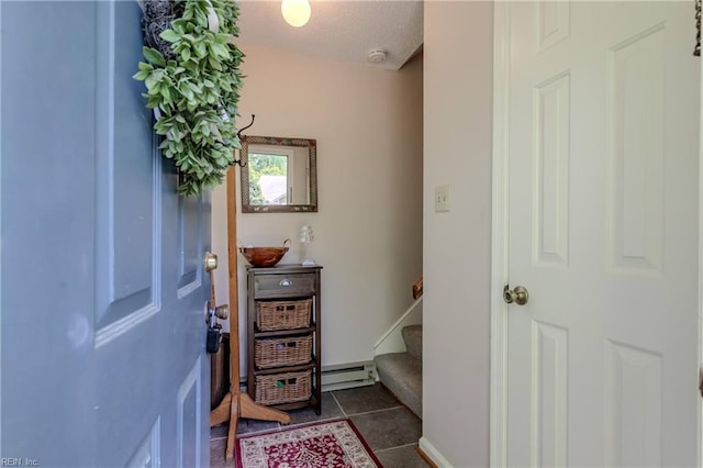 foyer with a baseboard radiator, stairs, and dark tile patterned flooring