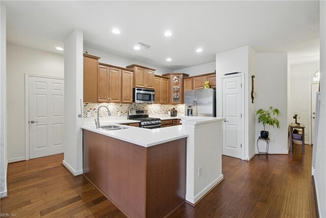 kitchen with a sink, dark wood finished floors, appliances with stainless steel finishes, and glass insert cabinets
