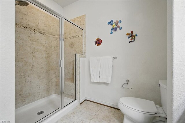 bathroom with tile patterned floors, baseboards, a shower stall, and toilet