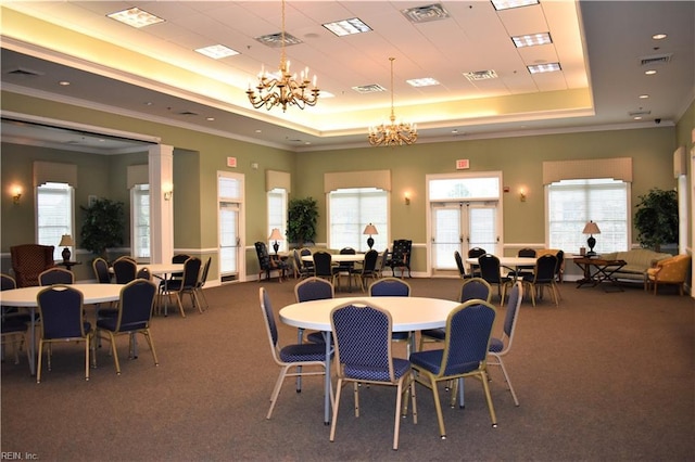 dining space featuring carpet flooring, a notable chandelier, a tray ceiling, visible vents, and ornamental molding