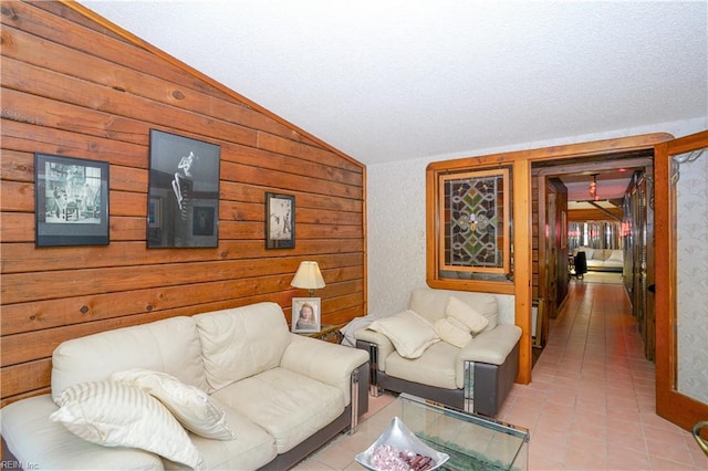 living room with a textured ceiling, light tile patterned floors, lofted ceiling, and wooden walls