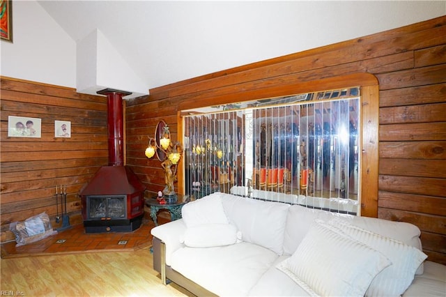 living room with vaulted ceiling, a wood stove, wood walls, and wood finished floors