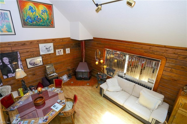 living room featuring wood walls, vaulted ceiling, wood finished floors, and a wood stove