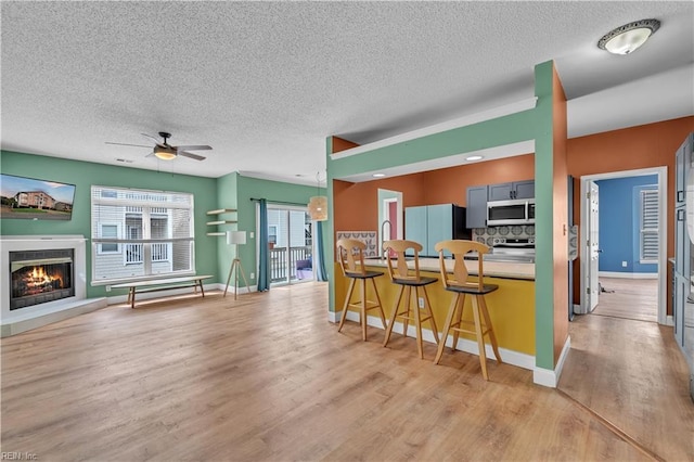kitchen featuring a textured ceiling, appliances with stainless steel finishes, ceiling fan, and light wood-type flooring