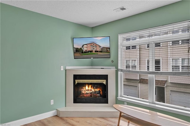details with baseboards, a lit fireplace, wood finished floors, and visible vents