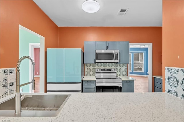 kitchen featuring visible vents, light countertops, tasteful backsplash, a sink, and stainless steel appliances