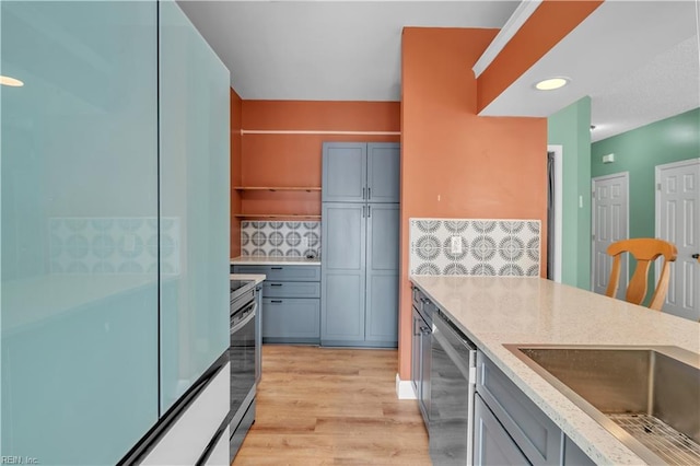 kitchen featuring open shelves, light wood finished floors, decorative backsplash, and stainless steel appliances