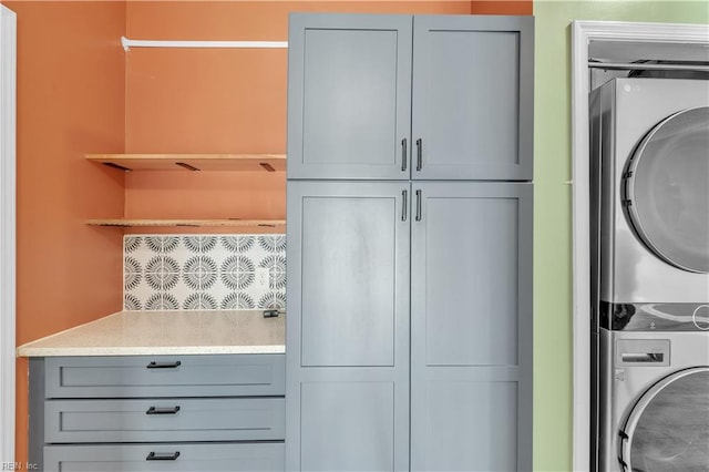 clothes washing area with cabinet space and stacked washing maching and dryer