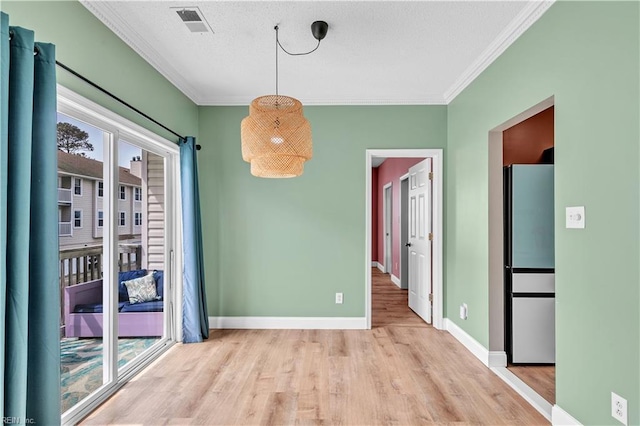 unfurnished dining area featuring a textured ceiling, visible vents, crown molding, baseboards, and light wood-style flooring