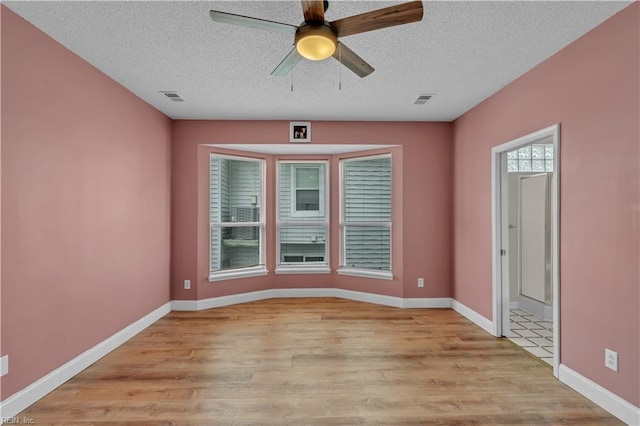 empty room with a textured ceiling, light wood-style flooring, and visible vents