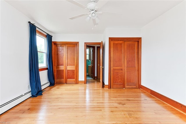 unfurnished bedroom with a ceiling fan, baseboards, baseboard heating, and light wood-style floors