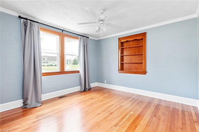 unfurnished room with wood-type flooring, crown molding, built in features, baseboards, and a ceiling fan