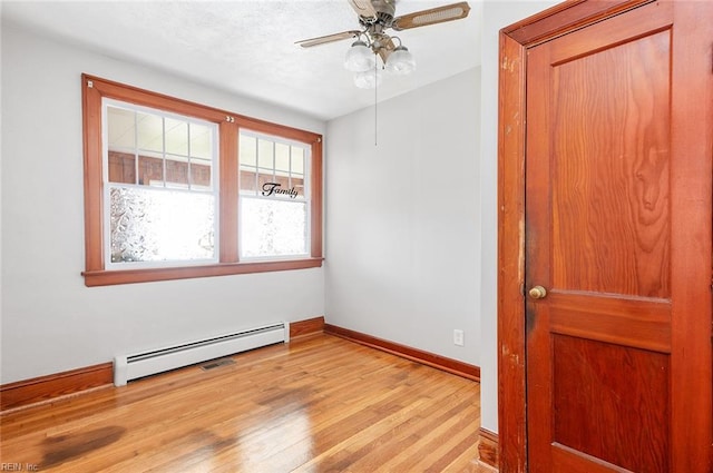 empty room with light wood-type flooring, a ceiling fan, baseboards, and a baseboard heating unit