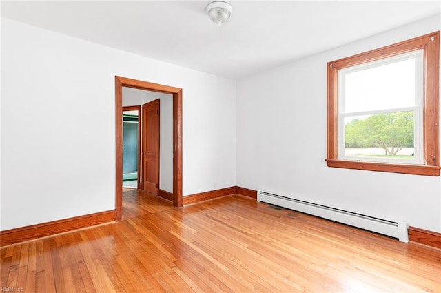 empty room with baseboards, a baseboard heating unit, and light wood-type flooring