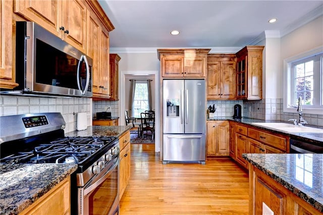 kitchen with a sink, appliances with stainless steel finishes, brown cabinets, and light wood-style flooring