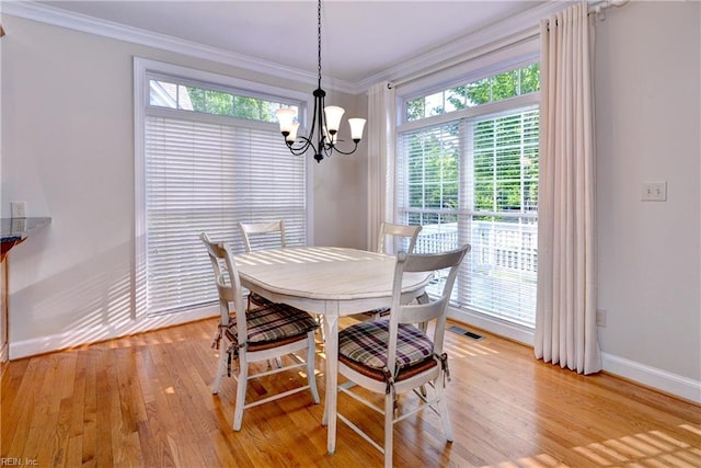 dining space with an inviting chandelier, baseboards, crown molding, and light wood finished floors