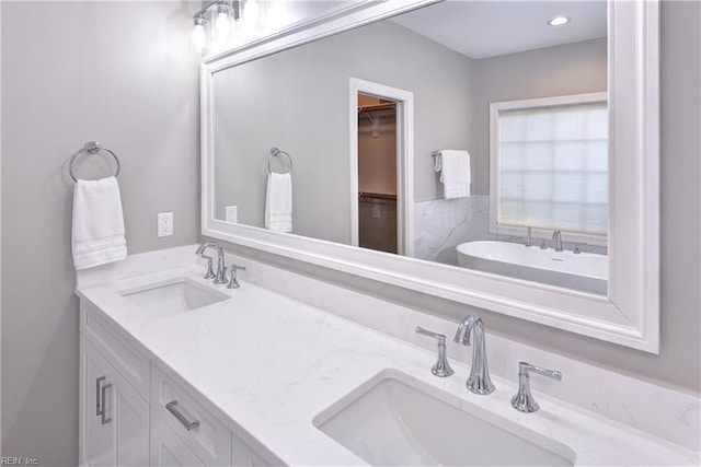 bathroom featuring double vanity, a sink, and a spacious closet