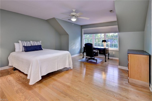 bedroom with baseboards, visible vents, lofted ceiling, and light wood finished floors