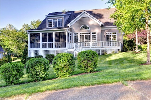 back of house with a sunroom, a lawn, roof with shingles, and a wooden deck