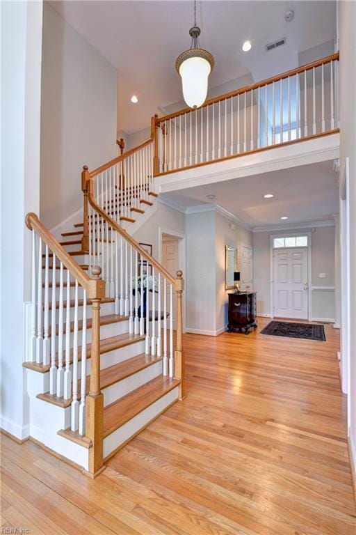 stairs with baseboards, visible vents, wood finished floors, and a towering ceiling