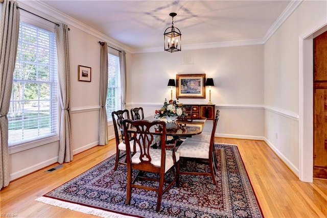 dining area featuring crown molding, plenty of natural light, wood finished floors, and visible vents