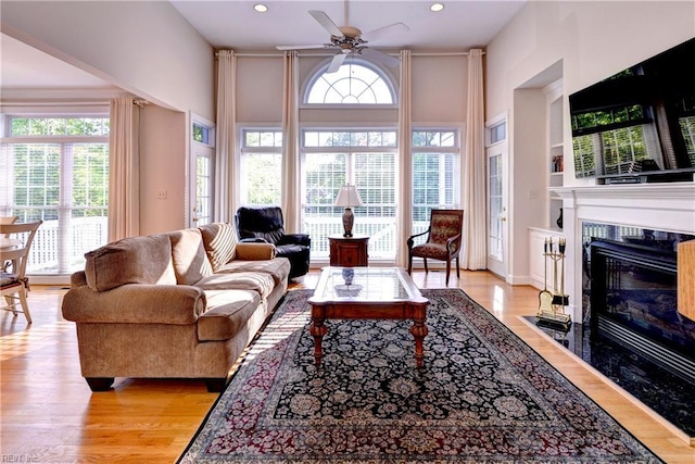 living room featuring recessed lighting, a ceiling fan, light wood finished floors, and a tile fireplace