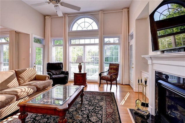 living room with light wood-style floors, a ceiling fan, and a premium fireplace