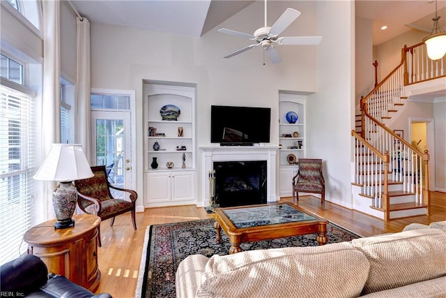living area featuring stairway, high vaulted ceiling, and light wood finished floors
