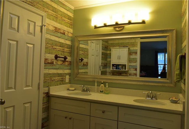full bath with double vanity, a sink, wooden walls, and ornamental molding
