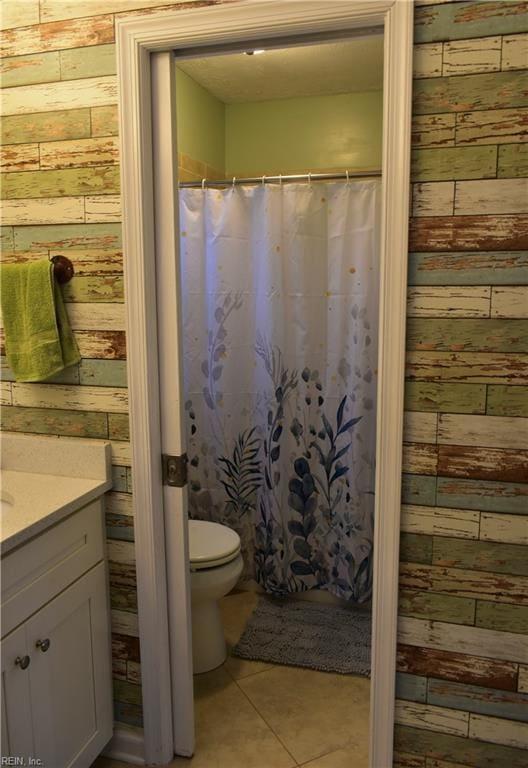 full bathroom with vanity, wood walls, tile patterned floors, and toilet