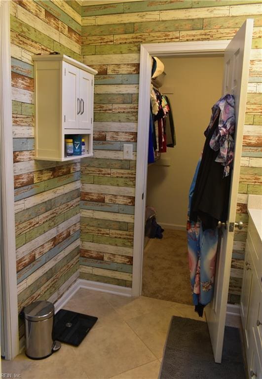 mudroom with wooden walls, tile patterned floors, and baseboards