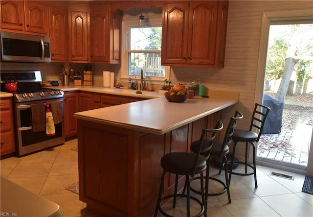 kitchen with a sink, light countertops, stainless steel appliances, a peninsula, and visible vents