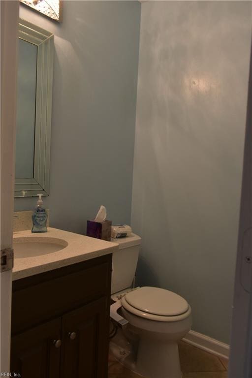 bathroom with toilet, tile patterned floors, baseboards, and vanity