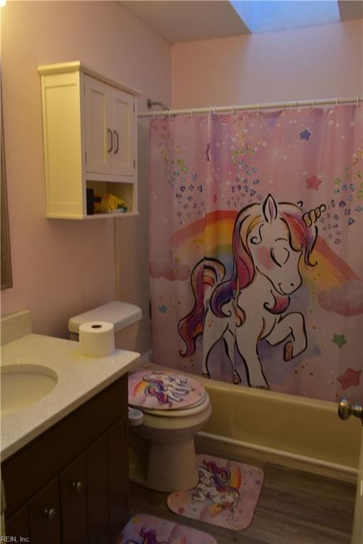 full bathroom featuring a skylight, wood finished floors, vanity, toilet, and shower / tub combo with curtain