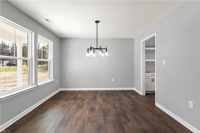 unfurnished dining area with baseboards, a notable chandelier, visible vents, and dark wood-type flooring