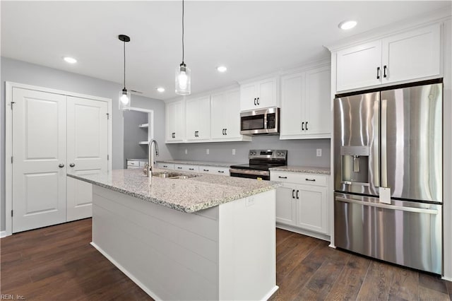 kitchen with a sink, white cabinets, appliances with stainless steel finishes, and a center island with sink