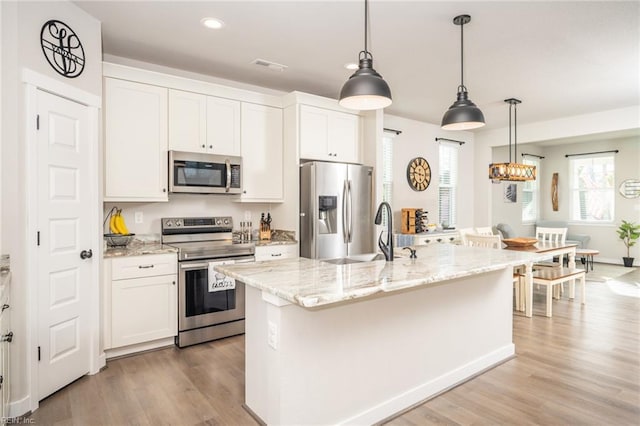 kitchen featuring an island with sink, light wood-style flooring, appliances with stainless steel finishes, and white cabinets