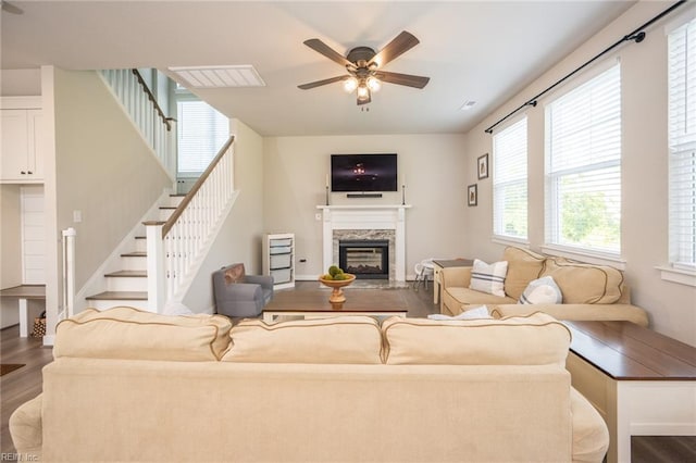 living room with a ceiling fan, visible vents, wood finished floors, stairs, and a premium fireplace