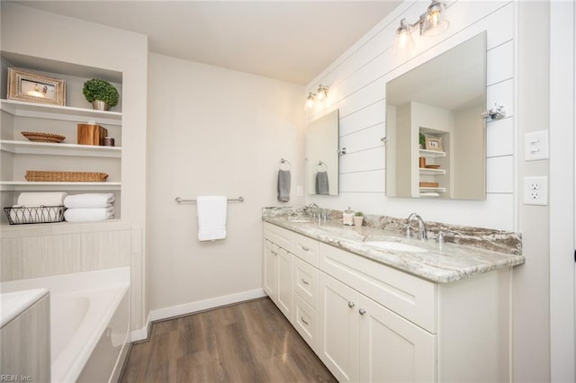 bathroom featuring a sink, baseboards, double vanity, and wood finished floors