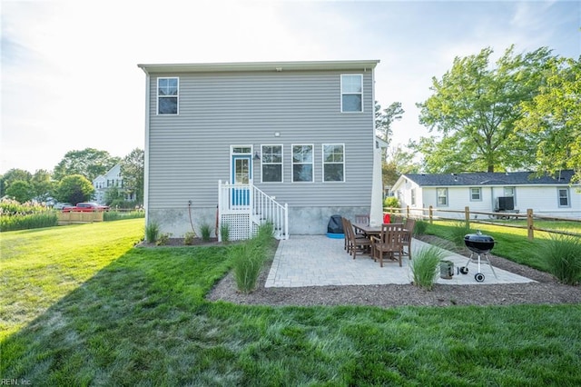rear view of house with fence, a yard, and a patio area
