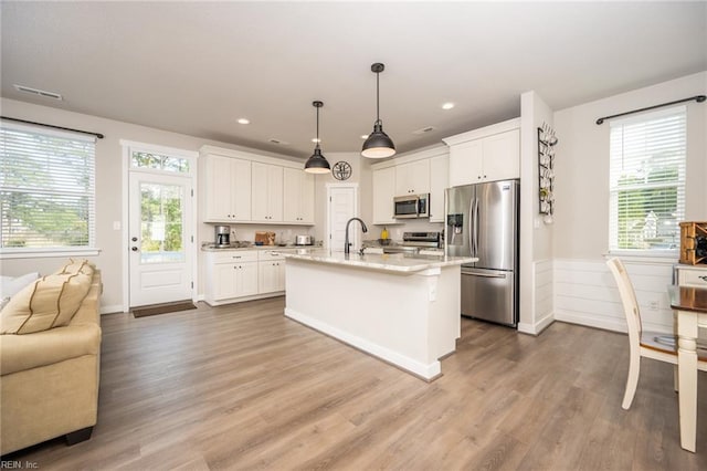 kitchen with open floor plan, white cabinets, light stone countertops, and stainless steel appliances