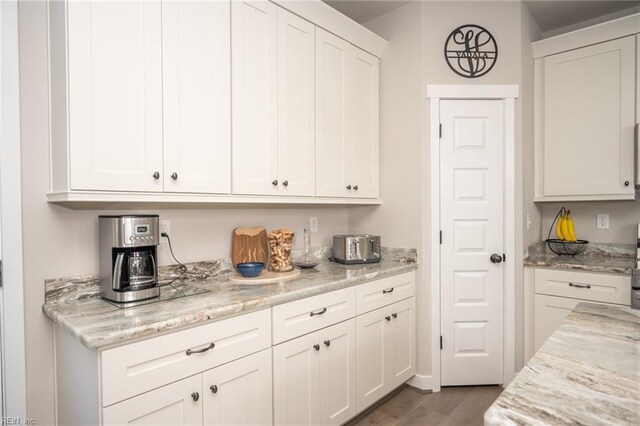 kitchen featuring light stone countertops, white cabinetry, and wood finished floors