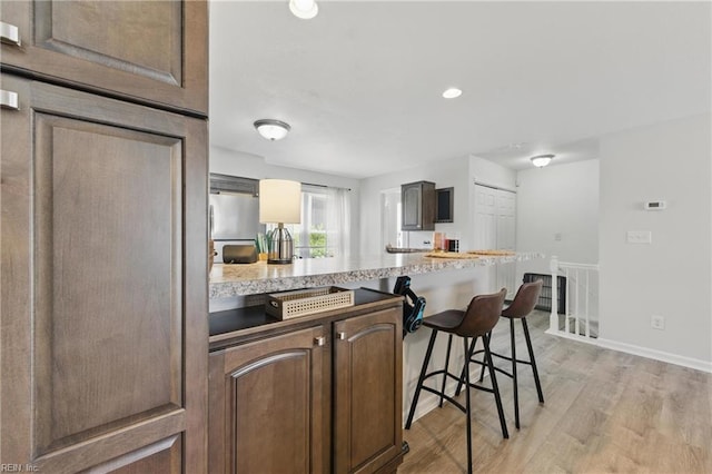 8550 Tidewater Dr Unit I2, Norfolk, VA 23503 - kitchen featuring a breakfast bar area, baseboards, a peninsula, light wood-style floors, and recessed lighting