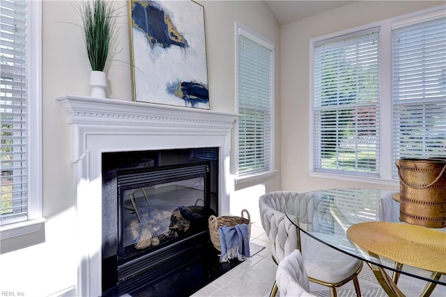 interior space with a healthy amount of sunlight, tile patterned flooring, and a glass covered fireplace