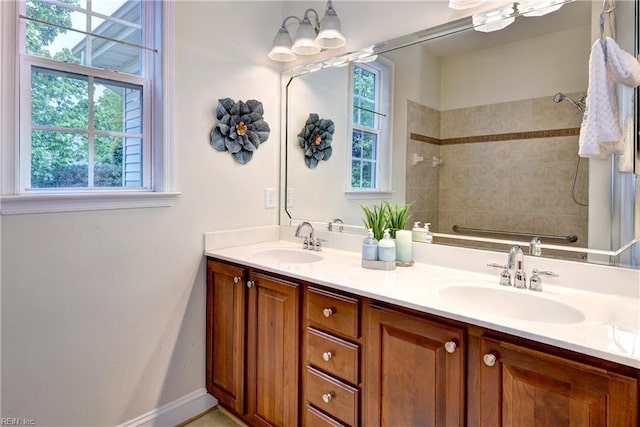 full bath featuring double vanity, a sink, and tiled shower