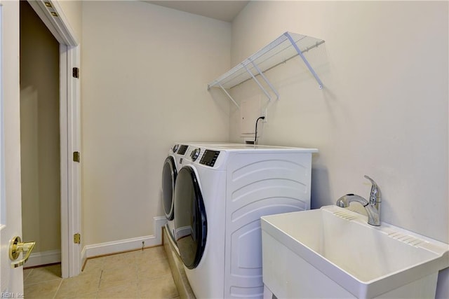 washroom featuring washer and dryer, light tile patterned flooring, laundry area, a sink, and baseboards