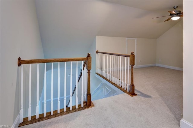 staircase featuring carpet floors, ceiling fan, baseboards, and lofted ceiling