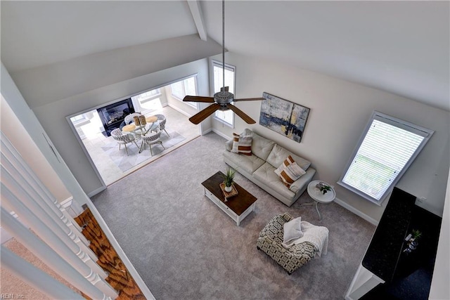 carpeted living room featuring vaulted ceiling with beams, plenty of natural light, a fireplace, and baseboards