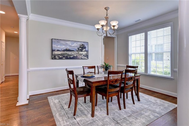 dining area featuring crown molding, an inviting chandelier, ornate columns, and wood finished floors
