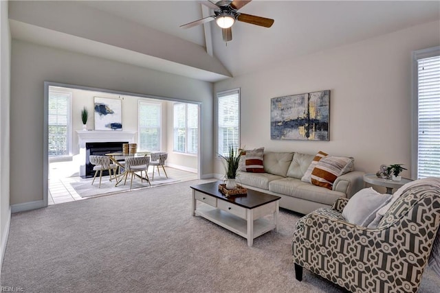 living room with baseboards, ceiling fan, vaulted ceiling, and carpet floors